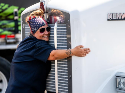 A woman hugs the front grill of a large white truck.